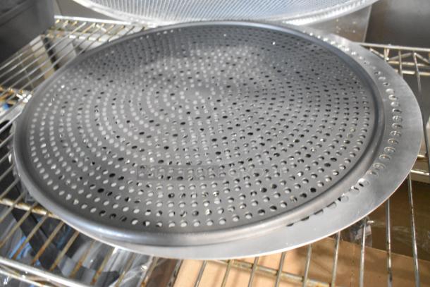 18 new scratch and dent items, including metal mesh pans and round perforated baking sheets on a metal rack.