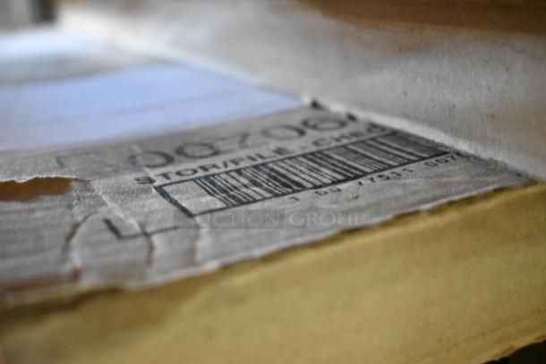 Close-up of a cardboard box with a visible barcode and partial text. Item includes scratch and dent items like a floor mat and dispenser.