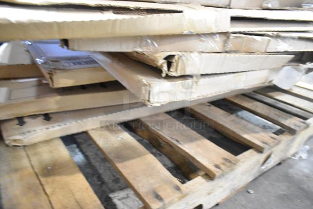 Stack of brand new scratch and dent items on a pallet, including an anti-fatigue mat and storage drawer, boxed.