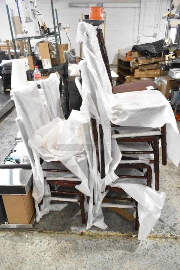 12 brand new scratch and dent wood-pattern dining chairs stacked, partially wrapped in protective material.