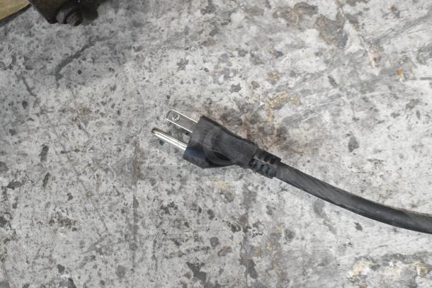 Power cord of the Bunn ICB-DV Tall Infusion Series Coffee Brewer on a concrete surface.