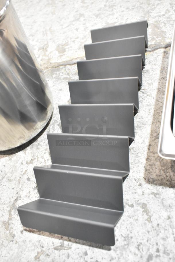 4 brand new scratch and dent items, including stainless steel drop-in bins and metal holder, on stone surface.
