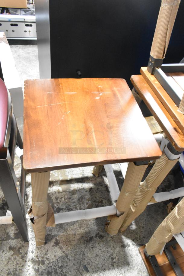 Five brand new scratch and dent bar height chairs, including four wooden stools and one black metal chair, slightly damaged.