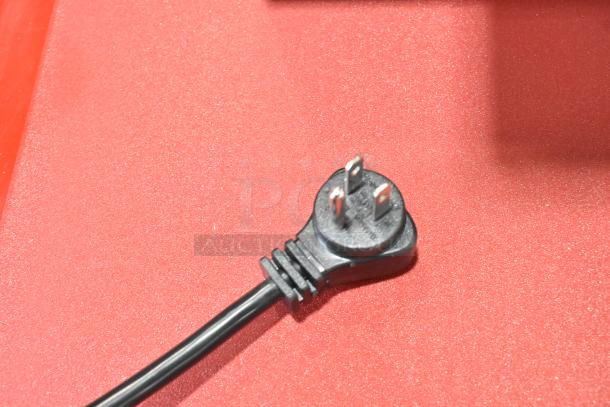 Close-up of a black three-prong plug on a red surface for the ServIt 423WDNBI2 drawer warmer.