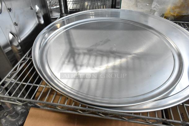 Set of metal mesh baking screens and round metal pans, brand new scratch and dent, on metal shelving.