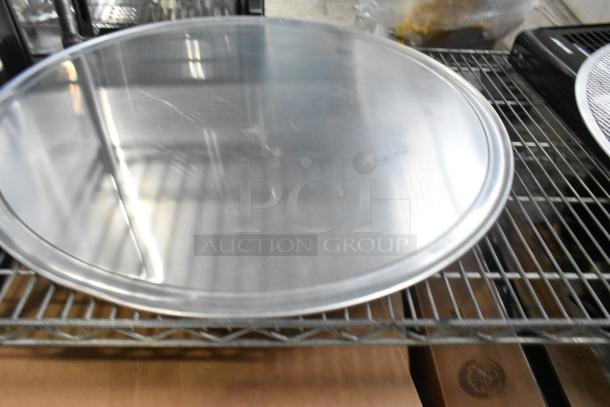 Five new metal baking items with minor scratches, including mesh screens and round pans on a wire rack.