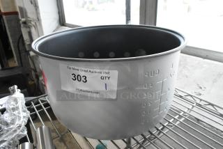 Brand new rice warmer insert with visible scratch and dent marks, numbered "303" from PCAAuctions.com, on metal shelf.