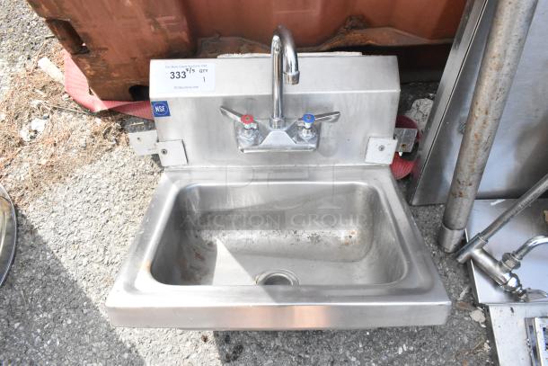 Stainless steel single bay sink with faucet and handles, featuring NSF label. Surface shows signs of use.