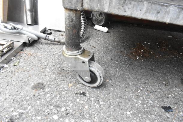 Stainless steel equipment stand with under shelf and commercial casters, showing a close-up of caster wheel.