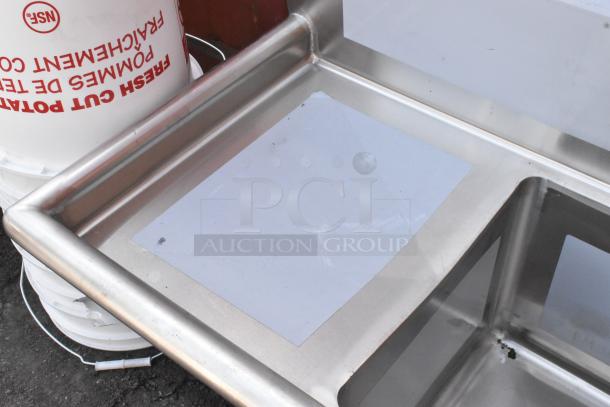 BRAND NEW Regency 600S31515215 stainless steel 3-bay sink with dual drain boards, no legs, visible surface imperfections.