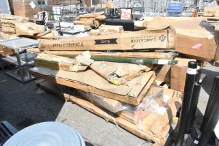 Assorted new scratch and dent items including an umbrella, stainless steel mixer table, and folding work table, boxed.