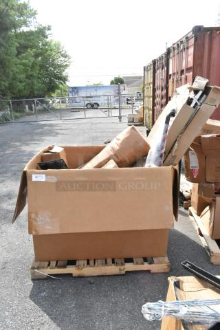 Cardboard box on pallet containing 14 scratch and dent items, including a grab bar and anti-fatigue floor mat. Tags indicate condition.
