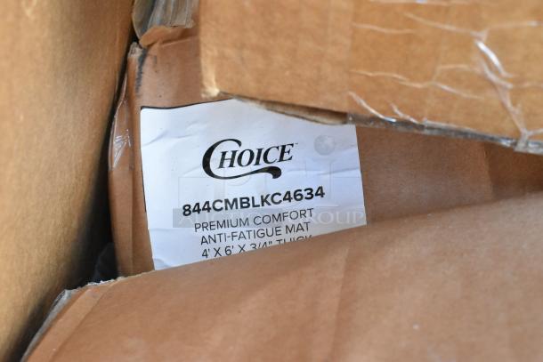 Cardboard box with visible label indicating "Choice 844CMBLKC4634 Premium Comfort Anti-Fatigue Mat, 4' x 6' x 3/4'' Thick."