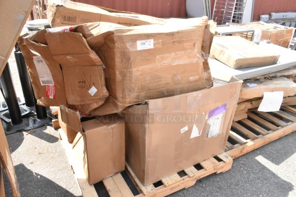 Four boxes of scratch and dent items, including a Steelton sink, cutting boards, and pizza pan, on a wooden pallet.