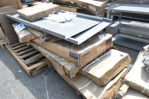 Eight brand new scratch and dent stainless steel equipment stands and tables, in original packaging, some damage visible.