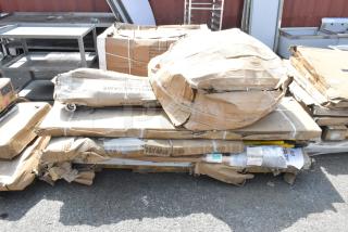 Brand new scratch and dent items including stainless steel overshelves and tables in damaged packaging on the ground.