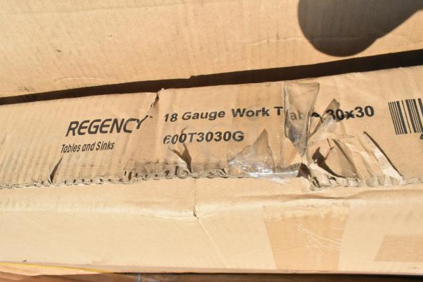 Cardboard box containing a Regency 18-gauge work table, model 600T3030G, with visible scratches and dents.