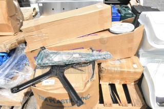 Assorted packaging containing seven new scratch and dent items, including cleaning brushes and trash cans, stacked on a pallet.