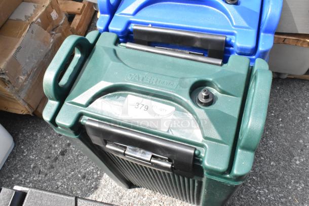 CaterGator 5-gallon green insulated beverage dispenser, new, with label "379 QTY VX2." Blue dispenser in background.