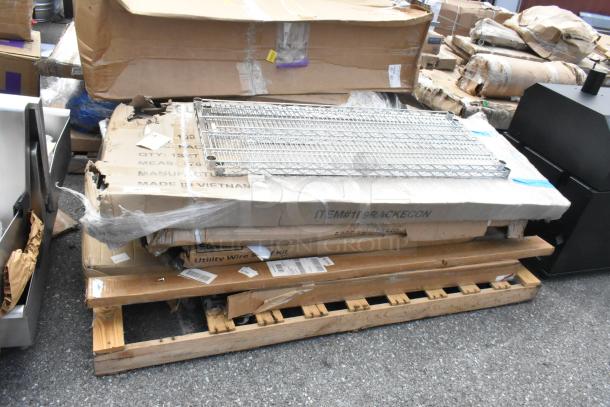 Eight brand new scratch and dent items including stainless stable, pan rack, and posts, packaged on pallet, visible wear on boxes.