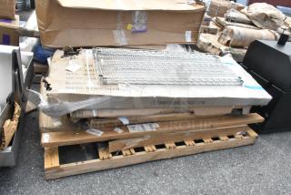 Eight brand new scratch and dent items including stainless stable, pan rack, and posts, packaged on pallet, visible wear on boxes.