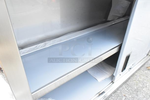 Brand new Regency 600WCS1548 48" stainless steel wall cabinet with sliding doors, slight scratches, dent visible, for storage.