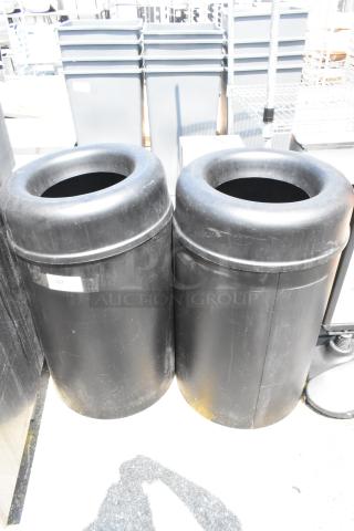 Two black trash can shells in good condition, featuring cylindrical design and open tops. One has a visible label.