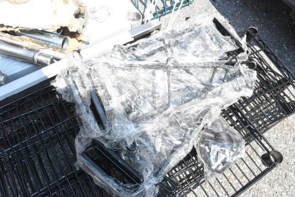 Lot of 8 brand new scratch and dent black finish wire shelves, partially wrapped in protective plastic.