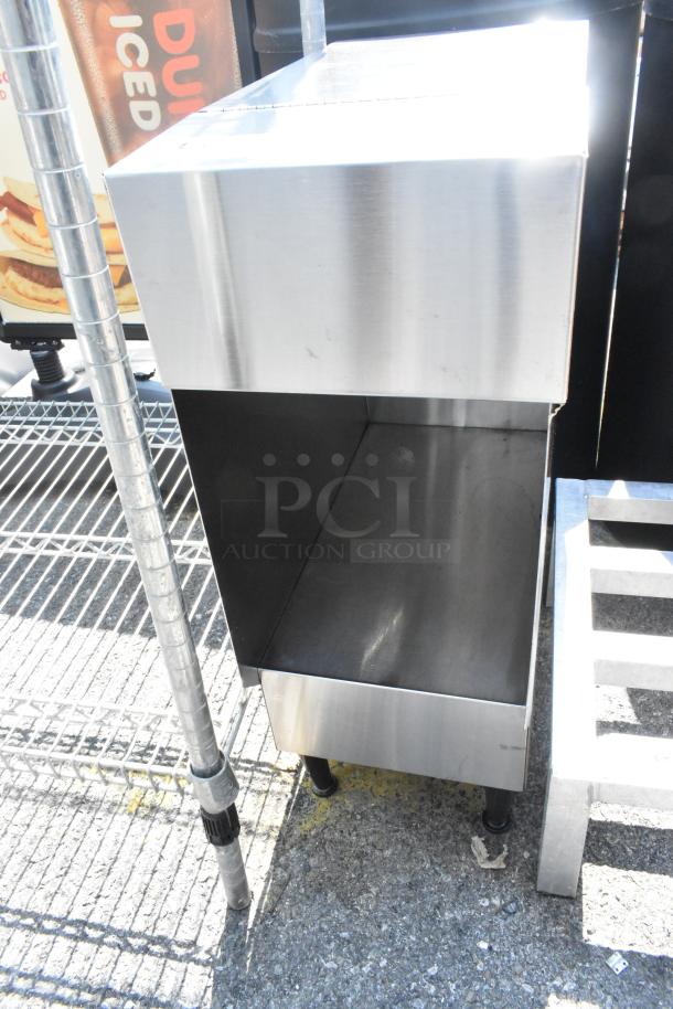 Stainless steel countertop dispenser stand with a sleek design, featuring sturdy black feet and a spacious compartment.