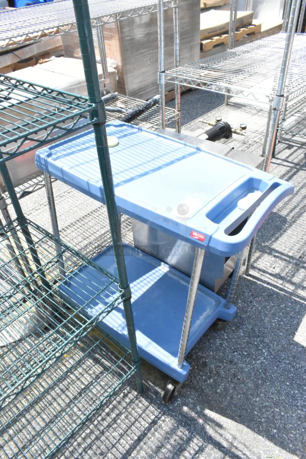 Metro Blue Poly 2 Tier Cart with commercial casters, new condition. Sturdy blue shelves, handles for easy transport.