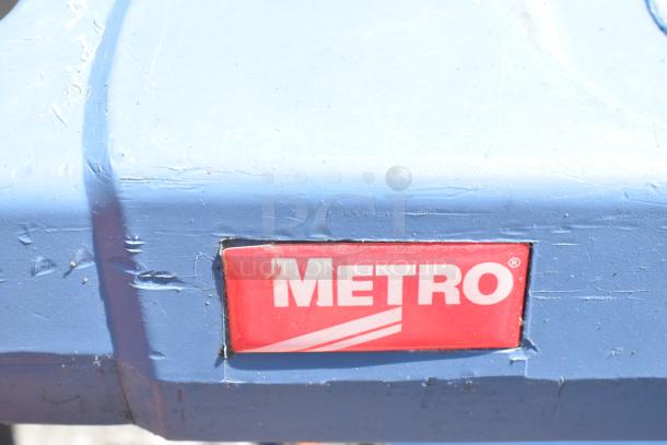 Metro Blue Poly 2 Tier Cart with commercial casters, showing the brand logo. Cart surface has visible wear marks.