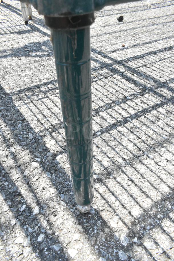 Metro green finish 3 tier wire shelving leg on rough ground, showing sturdy metal construction. Buyer must dismantle.