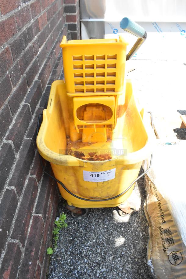 Yellow poly mop bucket with wringing attachment on commercial casters, visible wear, auction tag "419 1".