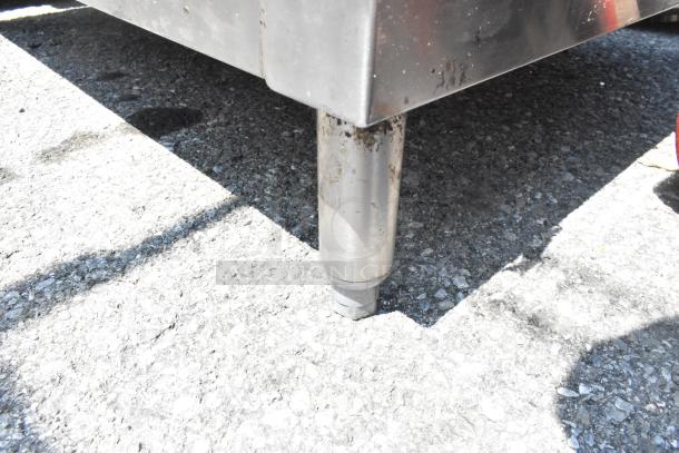 Stainless steel table leg with visible rust, indicating outdoor placement and wear.