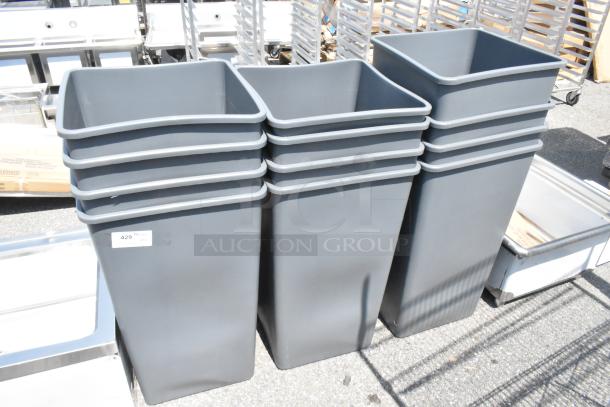 12 brand new gray poly trash cans with minor scratches visible. Stacked and ready for auction.