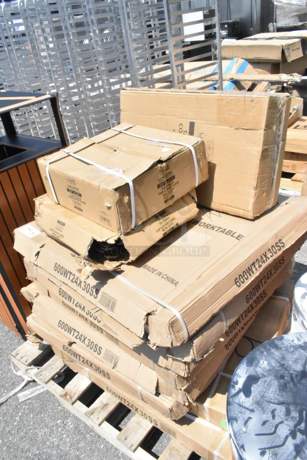 Damaged boxes of Regency 24"x30" stainless steel work tables and Lancaster cast iron table bases stacked on a pallet.