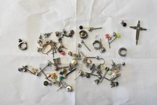 Lot of various jewelry, including mixed earrings, rings, and necklaces on a white background. Multiple styles and designs.