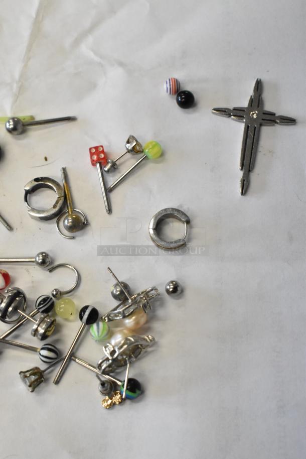 Lot of assorted jewelry including various metal earrings, colorful bead designs, and a cross-shaped pendant.
