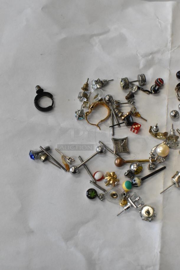 Lot of assorted jewelry including various stud earrings, a ring, and decorative pieces, mixed materials, shown on white background.