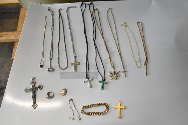 Lot of various jewelry including several necklaces with cross and leaf pendants, a bracelet, earrings, and a ring. Mixed materials and designs.