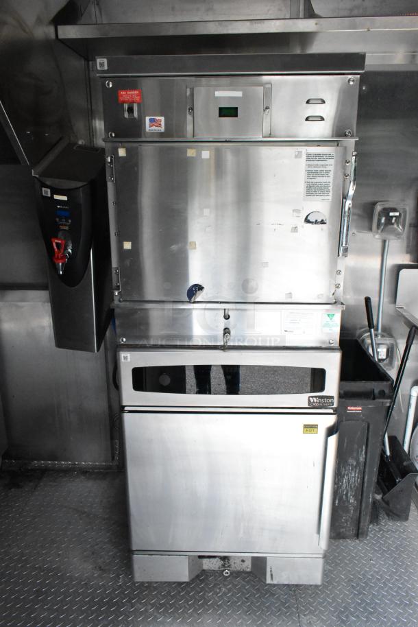 Stainless steel food trailer interior with Winston oven, water heater, and safety labels. Ready for use, well-maintained.