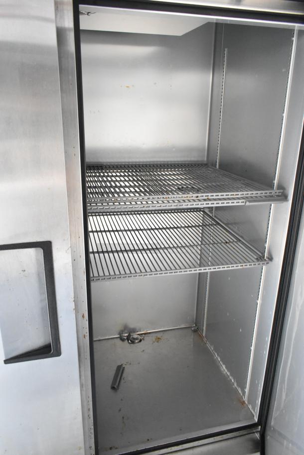 Stainless steel commercial fridge with open double doors, features wire shelves, minor wear inside. Ideal for food trailers.
