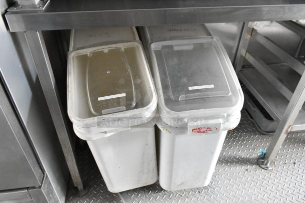 Food trailer storage bins under a stainless steel counter. Bins have clear lids with white labels. On diamond plate flooring.