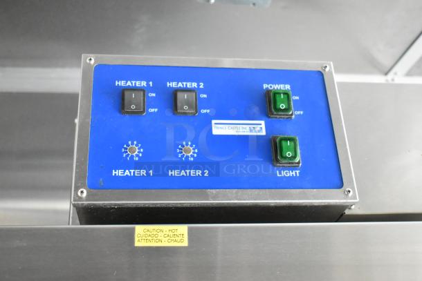 Control panel of food trailer showcasing Prince Castle Inc. fixtures. Features switches for heaters and lighting. Warning label for heat.