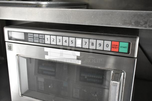 Stainless steel commercial microwave with numeric keypad, start/stop buttons, and clear glass door in excellent condition.