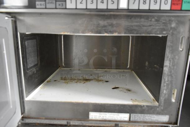 Interior of used microwave oven inside a food trailer. Shows wear with stained interior and visible control panel above.