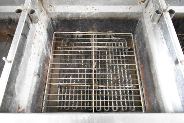 Close-up of industrial fryer inside a food trailer, showing metal grill and oil residue, indicating used condition.