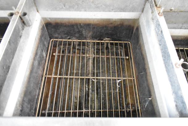 Interior of a commercial food fryer, showing metal grates and slightly used condition, part of a fully outfitted food trailer.