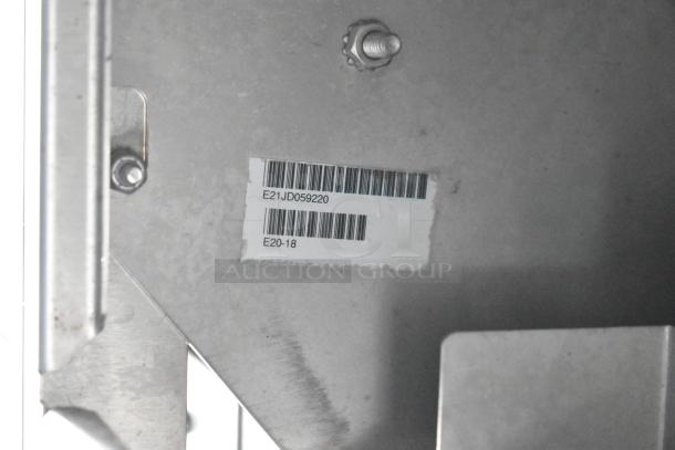 Metal surface with a label showing barcodes and codes "E21JD059220" and "E20-18". Part of a food trailer fixture.