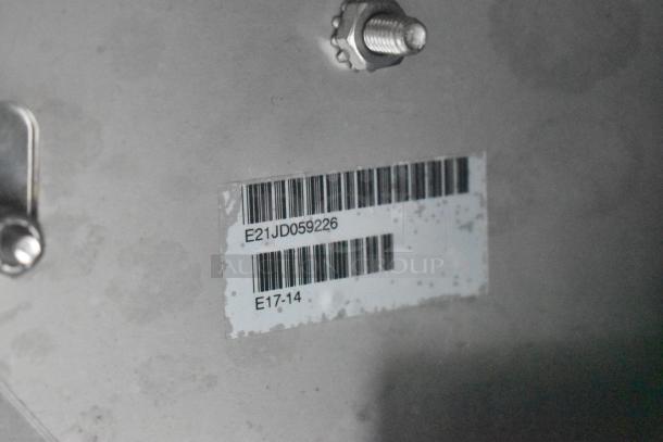 Barcode label on metal surface with code E21JD059226. Features bolt and visible fixture part.